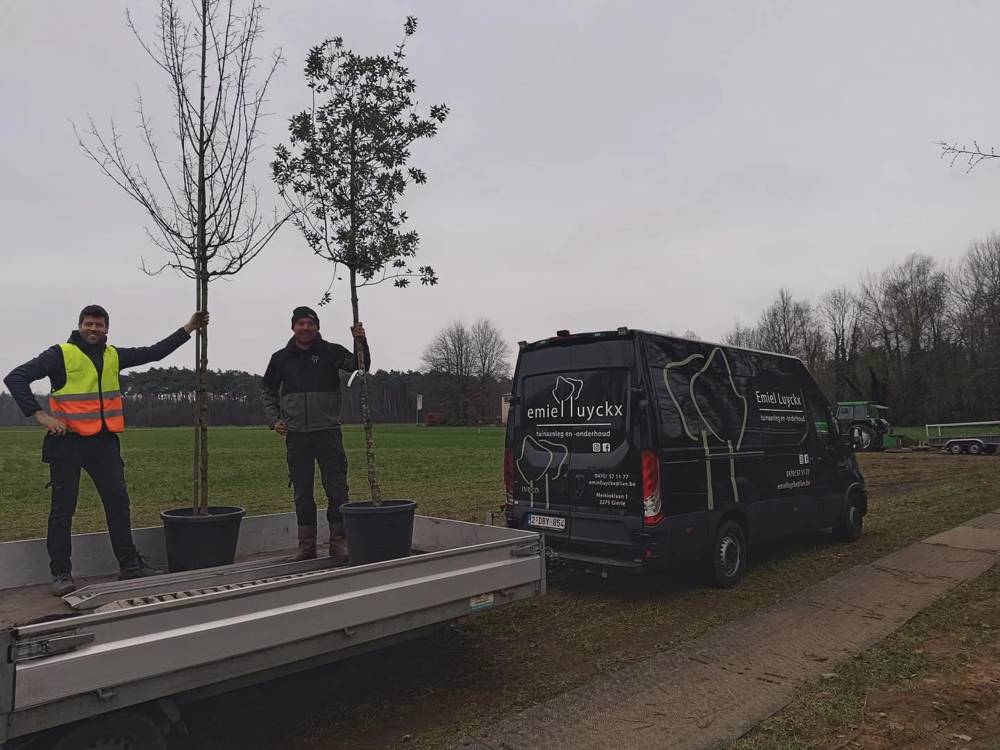 Team van Luyckx Tuinwerken met bomen op de aanhangwagen naast de bestelwagen